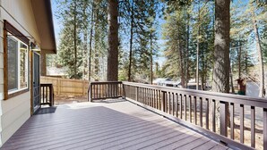 A wooden deck with a railing, overlooking a forested area. - Downtown McCall Retreat | Wood Stove & Deck (McCall)