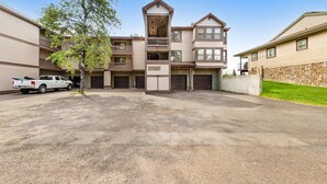 A multi-story residential building with a central tower, multiple balconies, and a garage area. - McCall Condo | Walk to Lake, Shops & Parks (McCall)