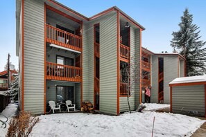 A multi-story building with a balcony, a small porch area, and a snow-covered ground. - Downtown McCall Condo | Fireplace + Balcony (McCall)
