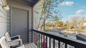 A porch with a view of a street, a door, and two chairs. - Downtown McCall Condo | Fireplace + Balcony (McCall)