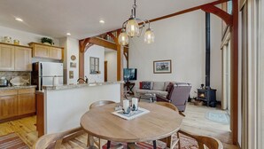 A kitchen with wooden cabinets, a refrigerator, and a dining area with a round table and chairs. - Golf Course Retreat | Patio & Near Downtown McCall (McCall)