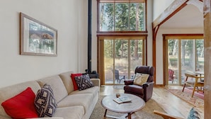 A cozy living room with a fireplace, a sofa, a leather armchair, and a dining area with a table and chairs. - Golf Course Retreat | Patio & Near Downtown McCall (McCall)