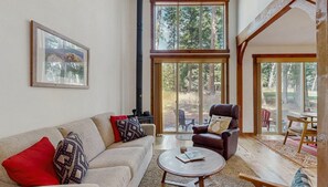 A cozy living room with a fireplace, a sofa, a leather armchair, and a dining area with a table and chairs. - Golf Course Retreat | Patio & Near Downtown McCall (McCall)