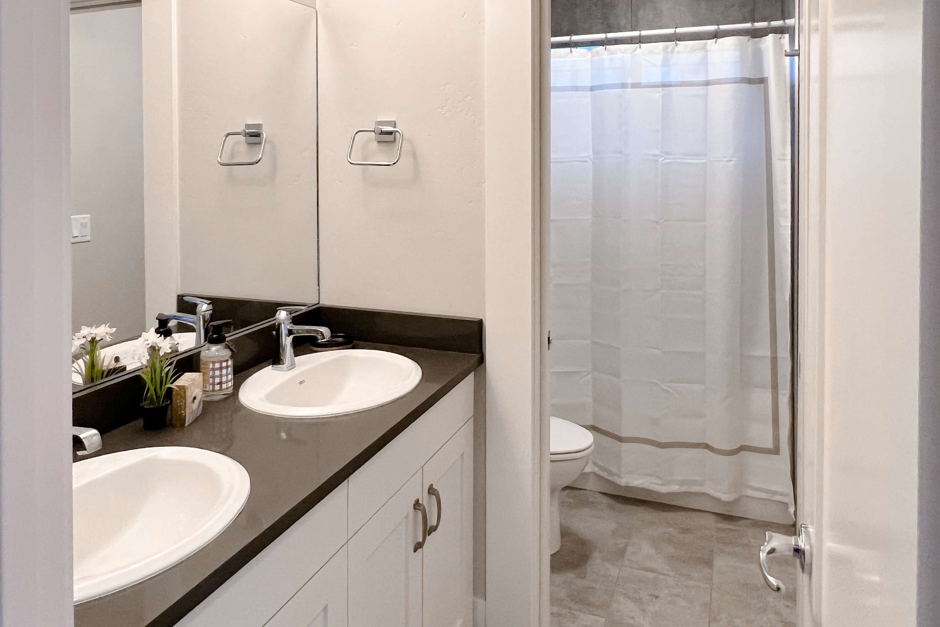 Un bagno con due lavandini, uno specchio e una tenda per la doccia.