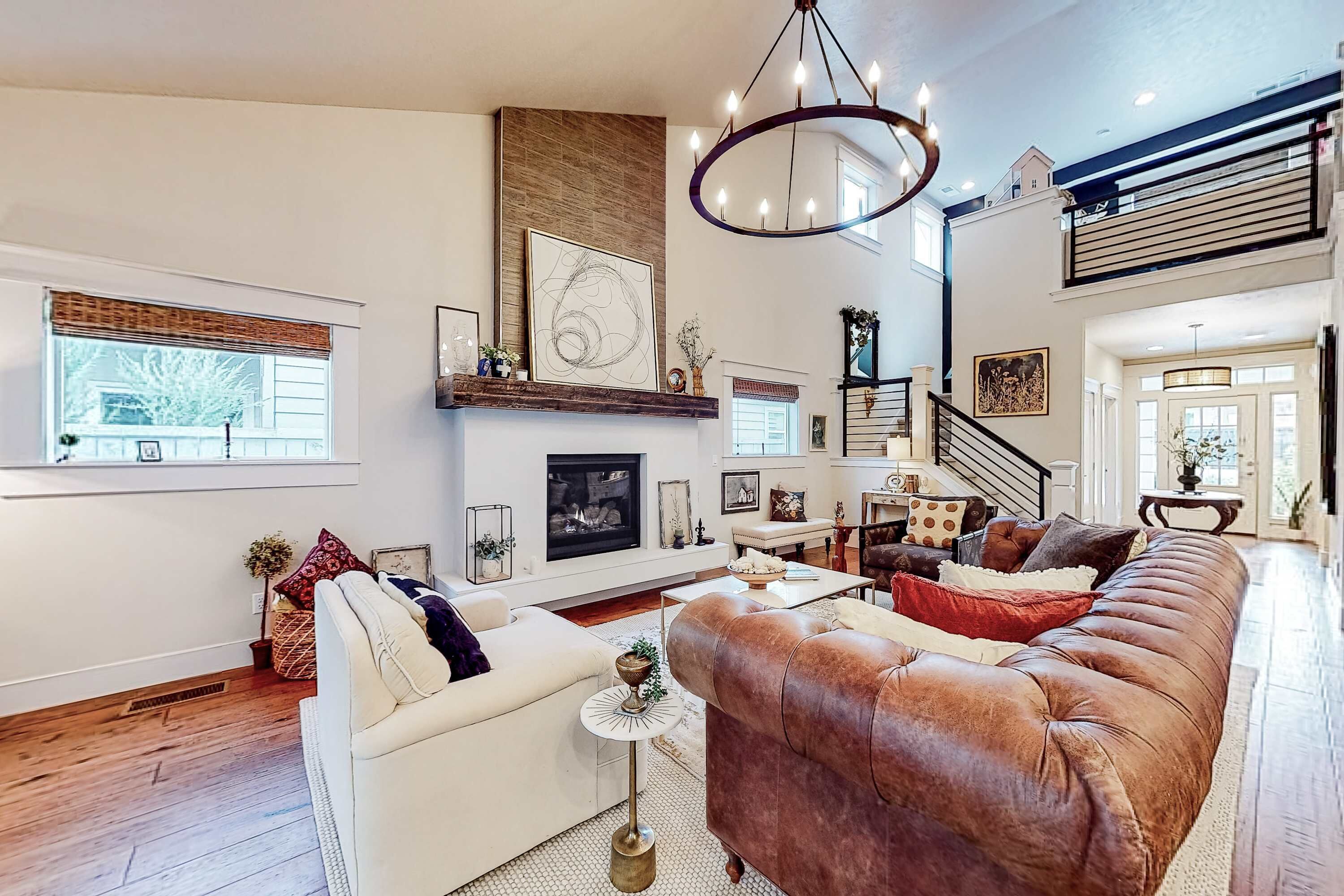 A spacious living room with a fireplace, a large leather sofa, and a chandelier.