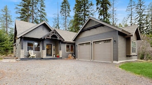 A two-story house with a garage, stone pillars, and a gravel driveway. - Modern McCall Home, 3 Kings, Firepit & Amenities (McCall)