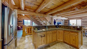 A spacious kitchen with wooden cabinets, a granite countertop, and a stainless steel refrigerator.