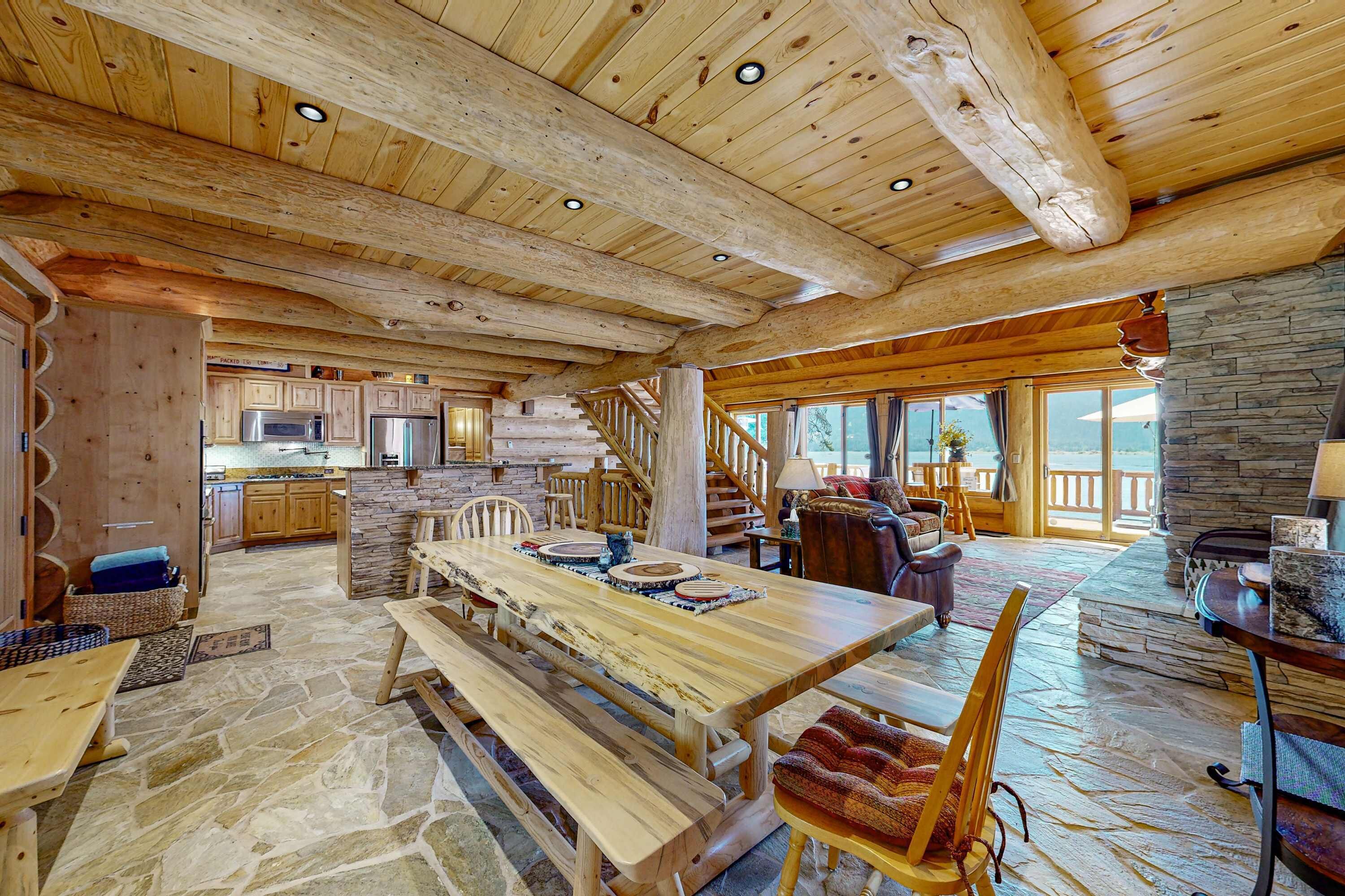 Una cocina amplia con vigas de madera, suelo de piedra y una gran mesa de comedor con bancos.