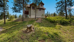 A two-story house with a porch, surrounded by trees and a grassy area.