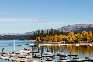 Un port de plaisance où sont amarrés des bateaux, entouré de montagnes et d’arbres aux couleurs automnales.
