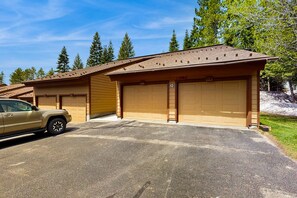 A single-story building with two garage doors, a parked SUV, and a clear sky. - Bright McCall Retreat - Pool, Hot Tub & Fitness (McCall)