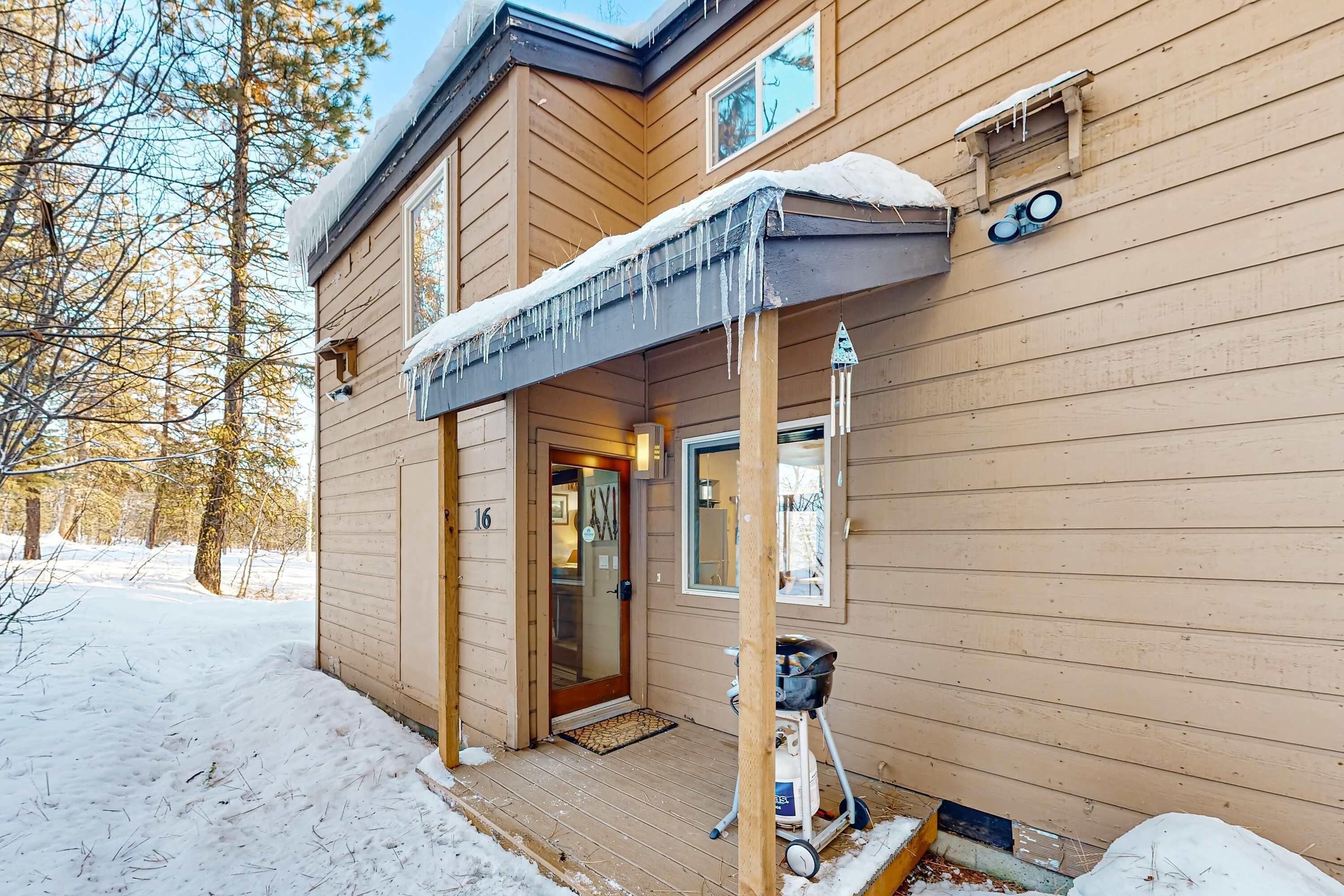 A wooden cabin with a covered porch, a door, and a small porch area with a cart.