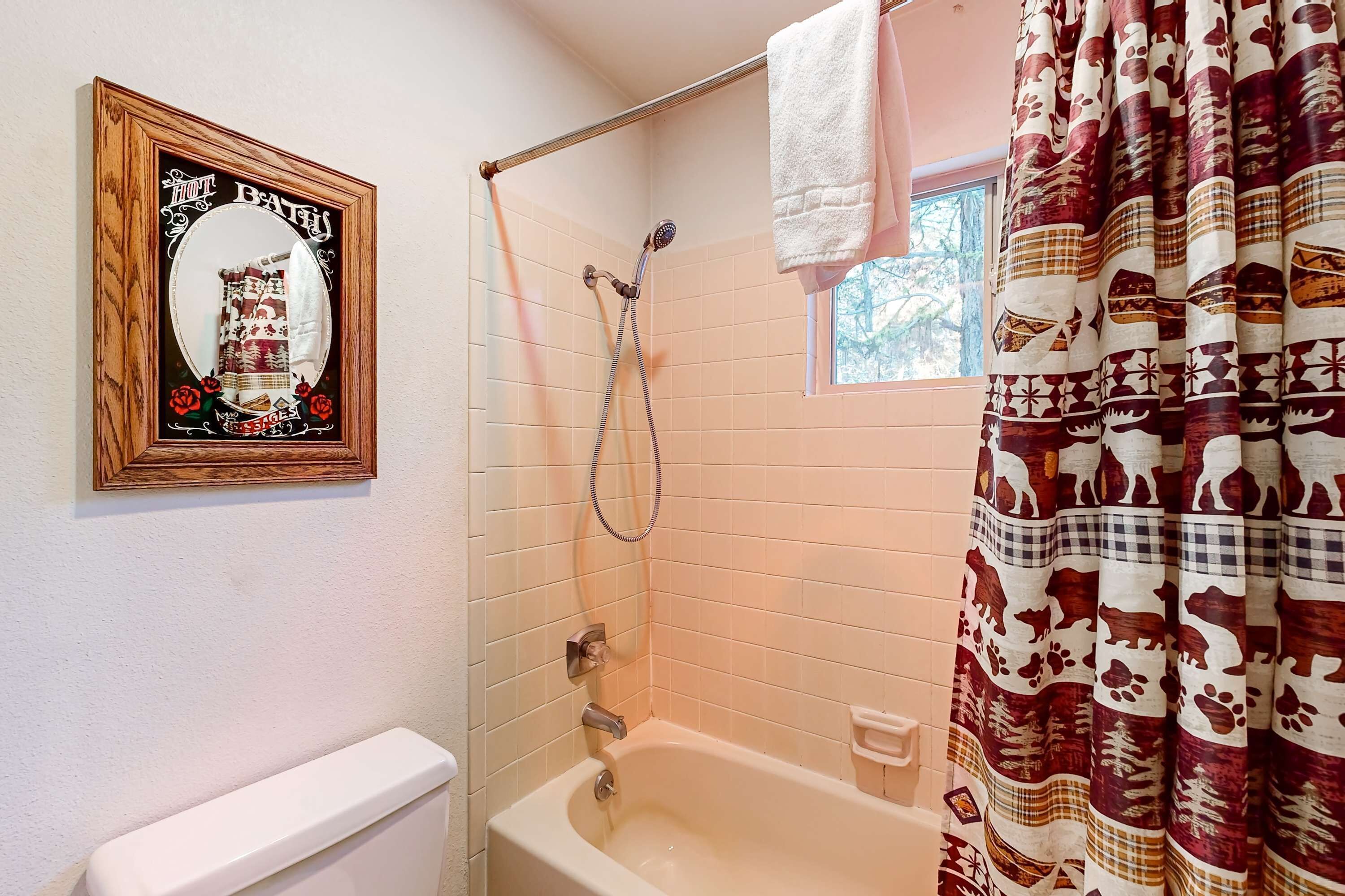 A bathroom with a shower, a toilet, and a framed mirror.