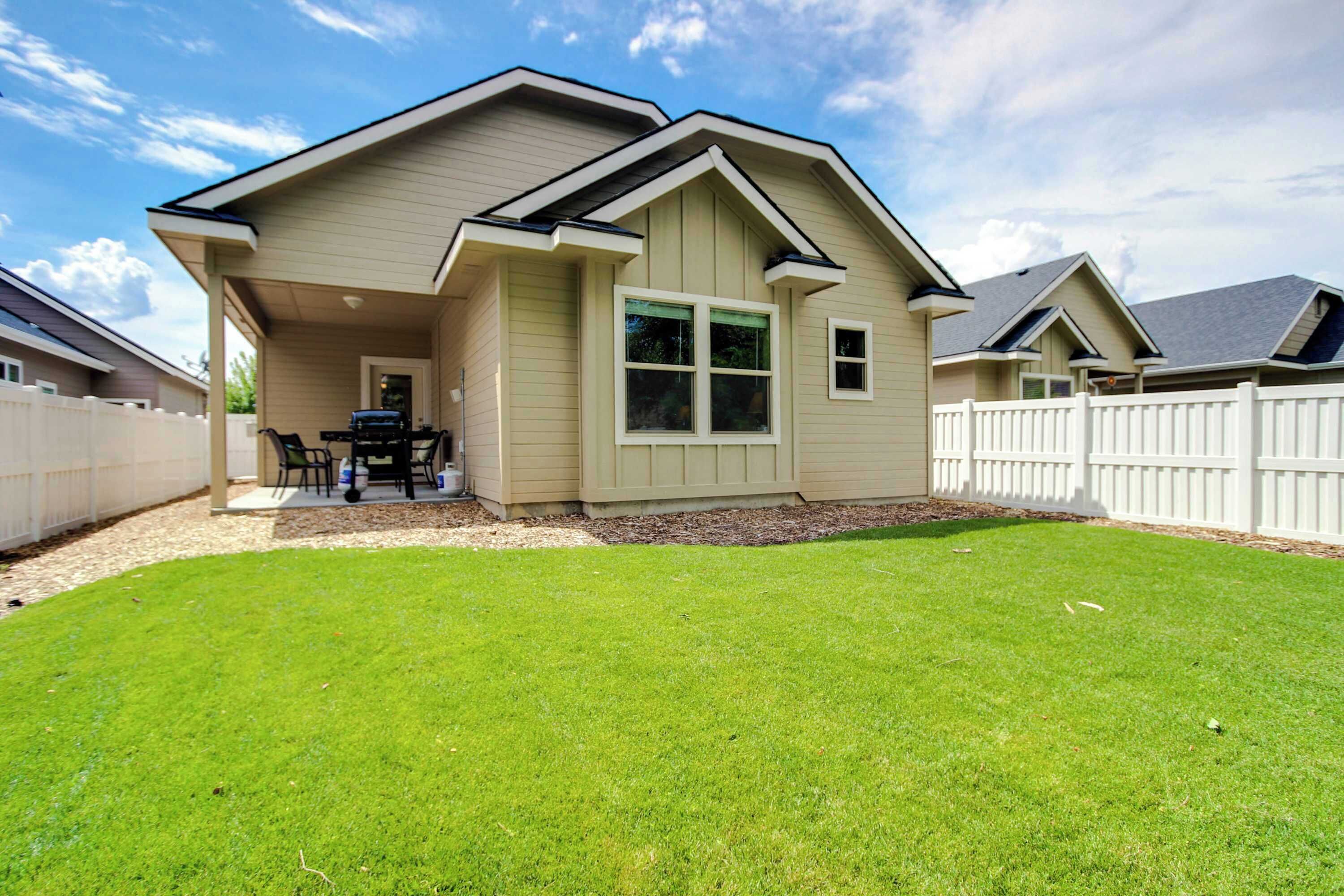 A two-story house with a covered patio, a fenced backyard, and a well-maintained lawn.