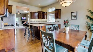 Una cocina amplia con armarios de madera, una isla central y un comedor con una mesa grande y sillas.