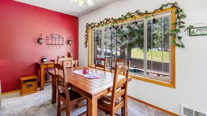 A dining area with a wooden table and chairs, a ceiling fan, and a window with a view of trees and a sign that reads "WELCOME TO OUR RE/MAX INN".