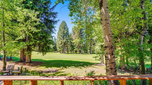A wooden bench overlooking a park with a grassy area and trees.