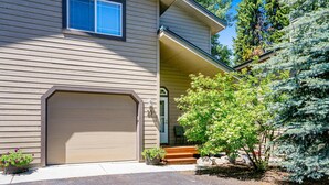 A two-story house with a beige exterior, a garage door, and a small front porch with steps.