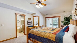 Ein Schlafzimmer mit einem hölzernen Bett, einem Deckenventilator und einem großen Fenster.