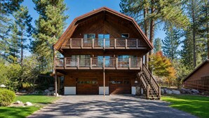 Eine zweistöckige Blockhütte mit einem Balkon, einer Garage und einer Treppe, die zum oberen Stockwerk führt.