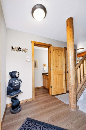 A wooden staircase with a handrail, a wooden door, and a wall-mounted sign that reads 'WELCOME FRIENDS'. - McCall 3 Bedroom Condo | Walk to Lake, Park & Golf (McCall)