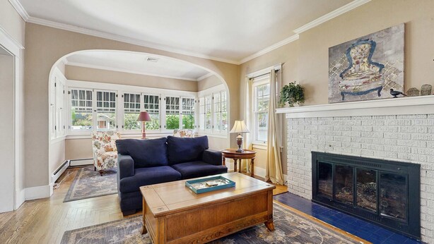 A living room with a fireplace, a blue sofa, and a coffee table. - Historic Craftsman Yard, Patio & Fireplace (Boise)