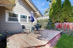 A wooden deck with outdoor furniture, a covered table, and a blue umbrella. - Historic Craftsman Yard, Patio & Fireplace (Boise)