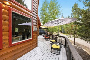 A wooden cabin with a deck, outdoor seating, and umbrellas. - 4BR McCall Cabin + Loft | Spring Mountain Ranch (McCall)