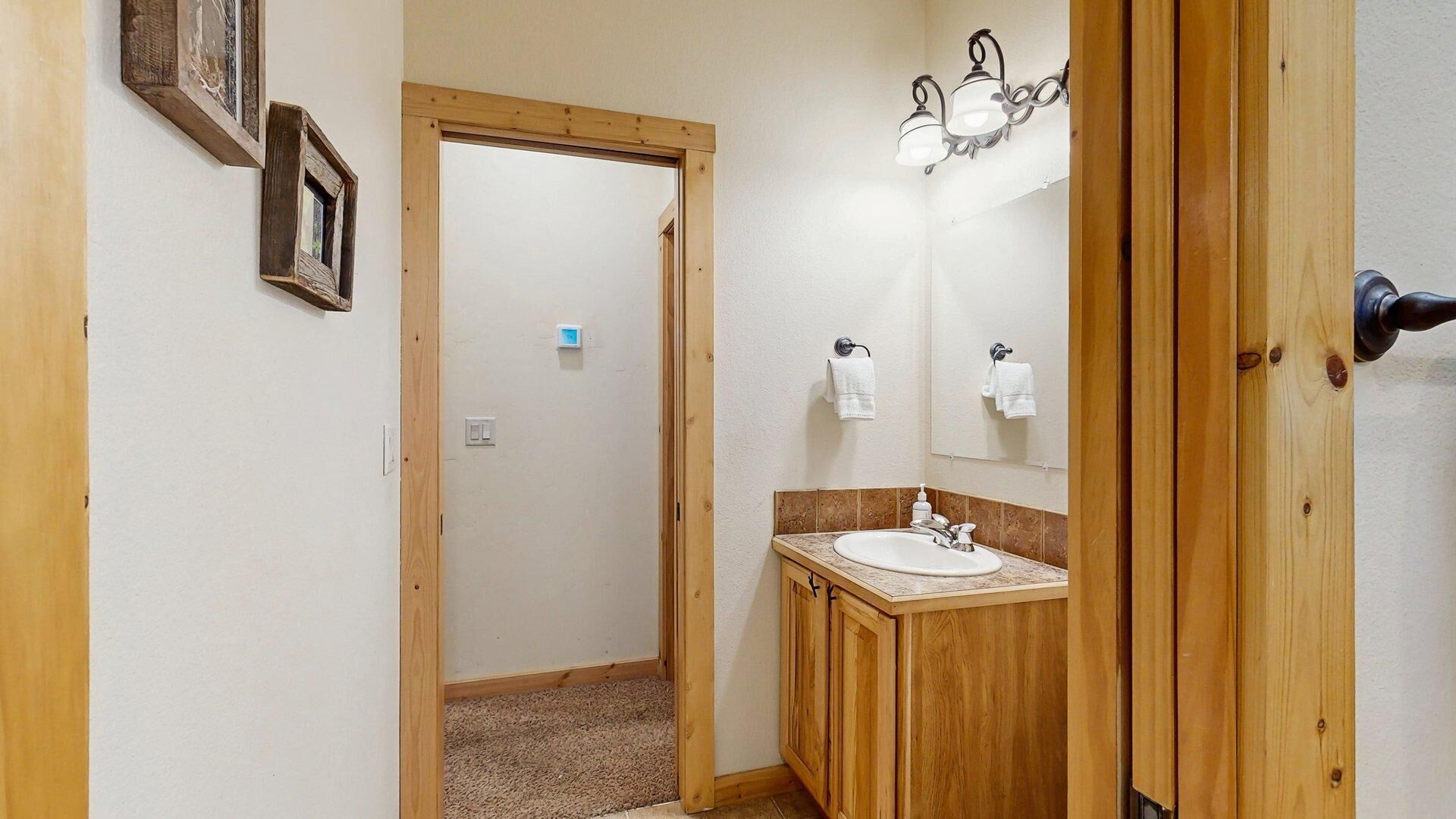 A bathroom with a wooden vanity, a sink, a mirror, and a light fixture.