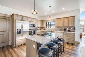 A spacious kitchen with a large island, stainless steel appliances, and wooden cabinets. - Luxury McCall Retreat | Hot Tub, Secret Bunk Room (McCall)