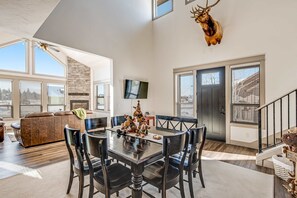 A spacious living area with a dining table, chairs, a sofa, and a mounted deer head. - Luxury McCall Retreat | Hot Tub, Secret Bunk Room (McCall)