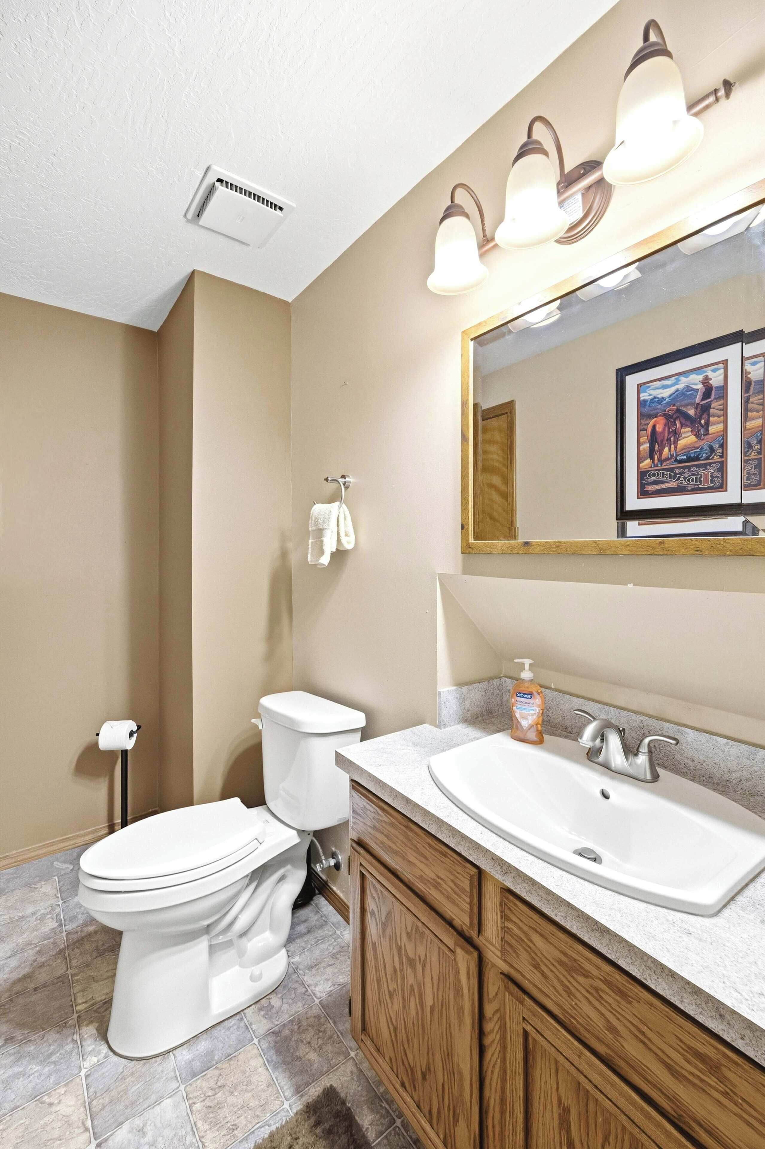 A bathroom with a toilet, sink, and mirror.