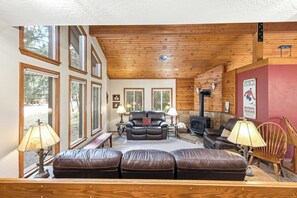 A cozy living room with leather sofas, a fireplace, and large windows.