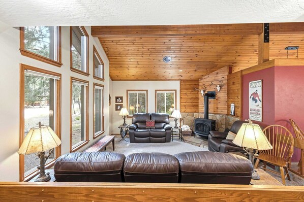 A cozy living room with leather sofas, a fireplace, and large windows.