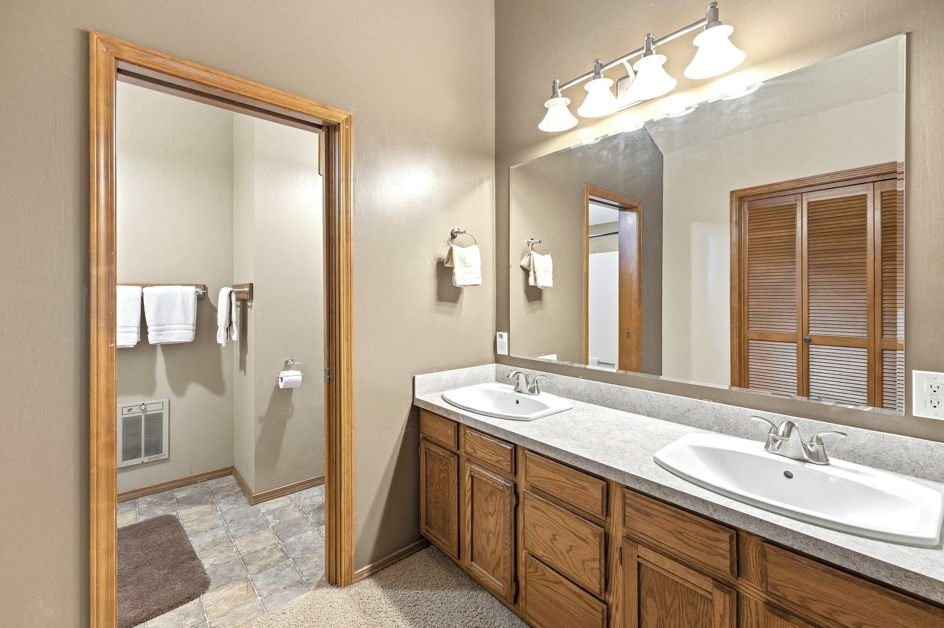 A modern bathroom with two sinks, a large mirror, and a walk-in shower.