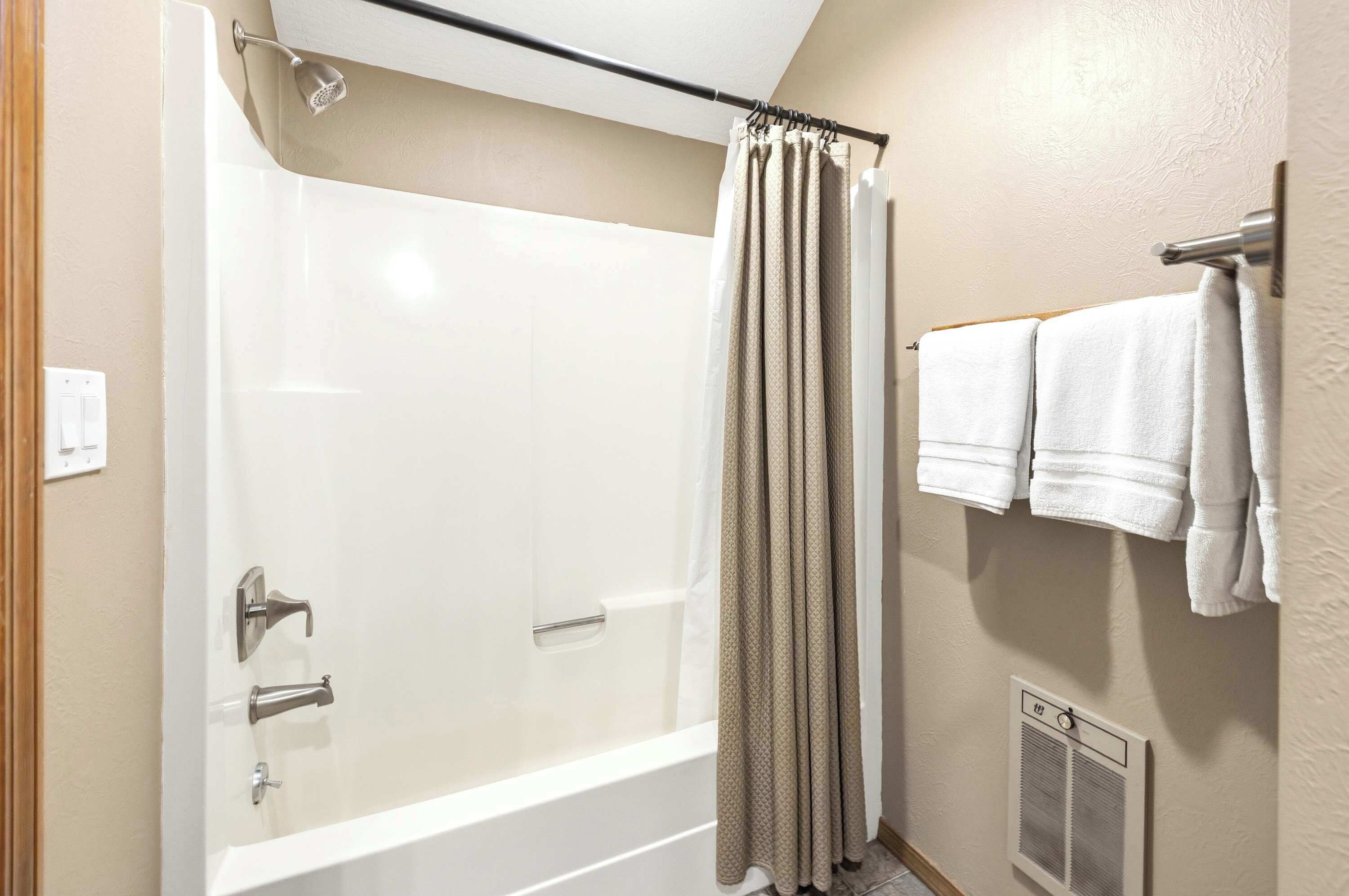 Baño con cabina de ducha a ras, toallero con dos toallas y calentador de pared.