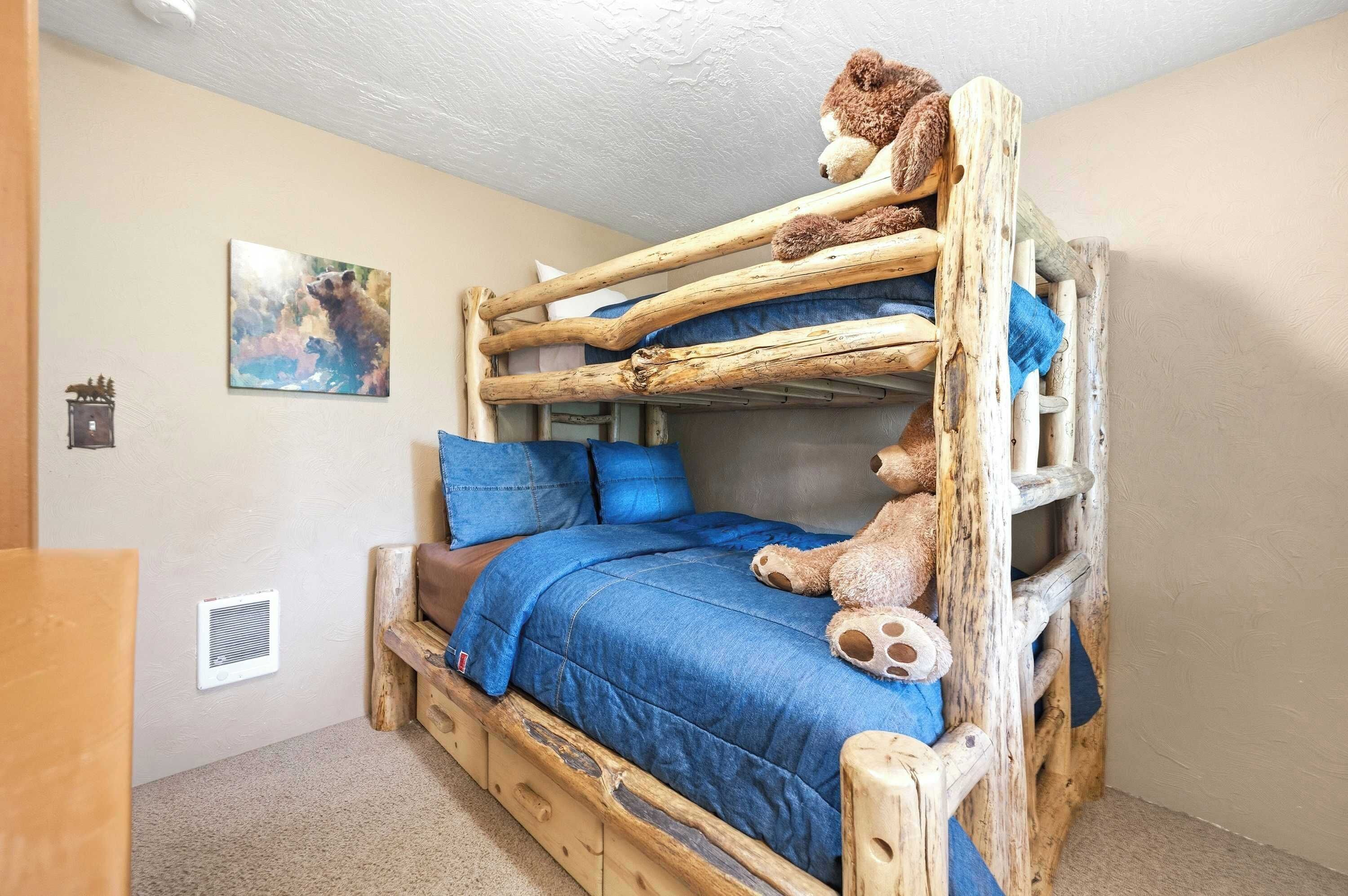 Una cama litera con un oso de peluche en la cama superior y un cuadro en la pared.