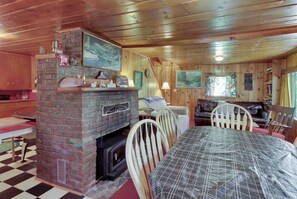 Ein gemütliches Blockhaus-Interieur mit Kamin aus Ziegelsteinen, einem Holzespeisetisch und einer Couch.