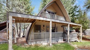 A two-story wooden cabin with a balcony on the upper floor, a covered porch, and a visible mailbox. - Downtown McCall A-Frame Cabin | Walk to Lake (McCall)
