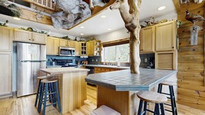 Une cuisine moderne avec des meubles en bois, un réfrigérateur en acier inoxydable, un four à micro-ondes et un grand îlot central doté de tabourets.