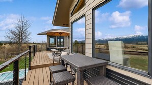 A deck with outdoor furniture, a glass enclosure, and a mountain view. - Luxury Mountain View Retreat | Hot Tub & Game Room (McCall)