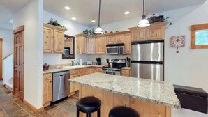 A modern kitchen with wooden cabinets, stainless steel appliances, and a granite countertop. - McCall Golf Course Condo | Pools, Hot Tub & Patio (McCall)