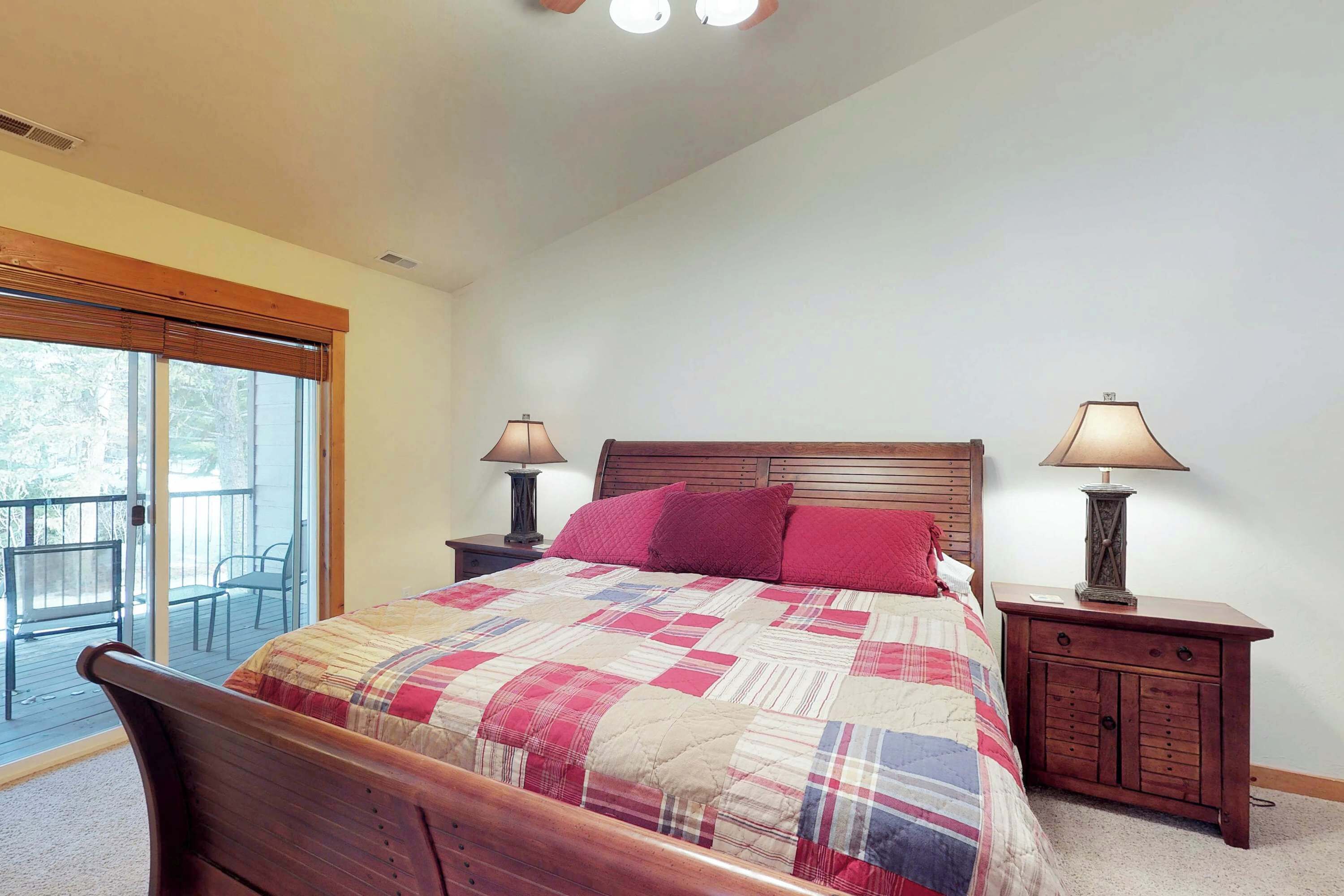 Un dormitorio con una cama de madera, un balcón y dos lámparas de noche.