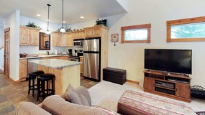 A modern kitchen with wooden cabinets, stainless steel appliances, and a central island with bar stools. - McCall Golf Course Condo | Pools, Hot Tub & Patio (McCall)