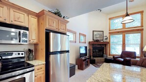 A kitchen with wooden cabinets, stainless steel appliances, a granite countertop, and a fireplace. - McCall Golf Course Condo | Pools, Hot Tub & Patio (McCall)