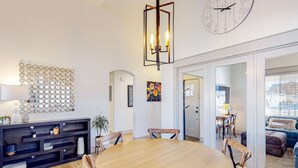 A spacious dining area with a round wooden table and chairs, a dark console table with decorative items, and a wall-mounted clock. - Spacious Meridian Retreat Near Parks & Golf (Meridian)