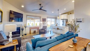 A modern living room with a sofa, coffee table, and a TV. There is a kitchen area with cabinets and a dining table. - Spacious Meridian Retreat Near Parks & Golf (Meridian)
