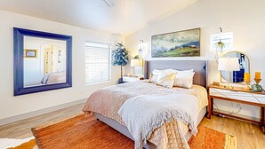 A bedroom with a large bed, a nightstand with a lamp, a mirror, and a painting on the wall. - Spacious Meridian Retreat Near Parks & Golf (Meridian)
