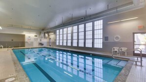 Piscina interior com pistas demarcadas, cadeira do salva-vidas e sinal de saída.