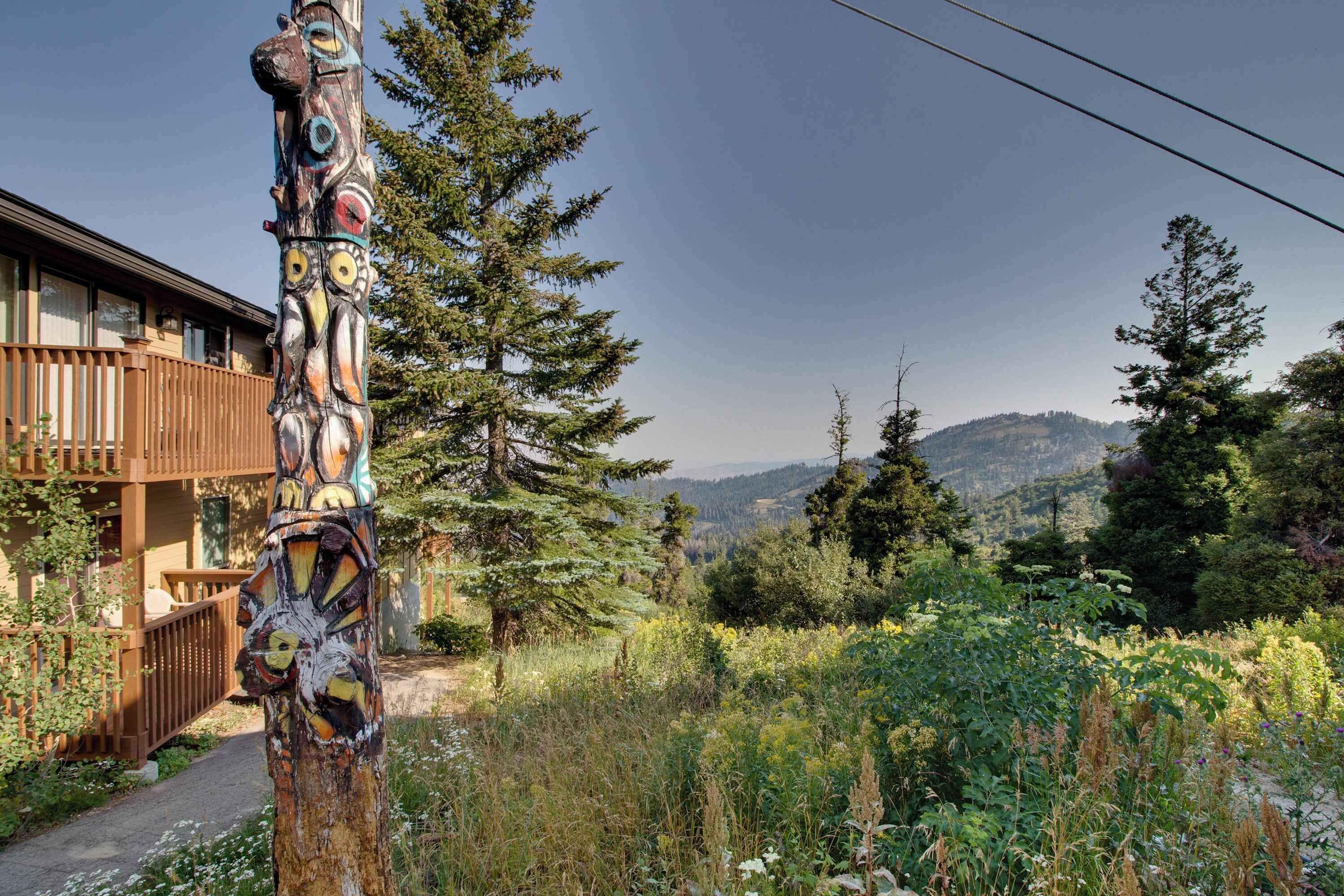 A rustic lodge with a wooden deck and a view of a forested valley.